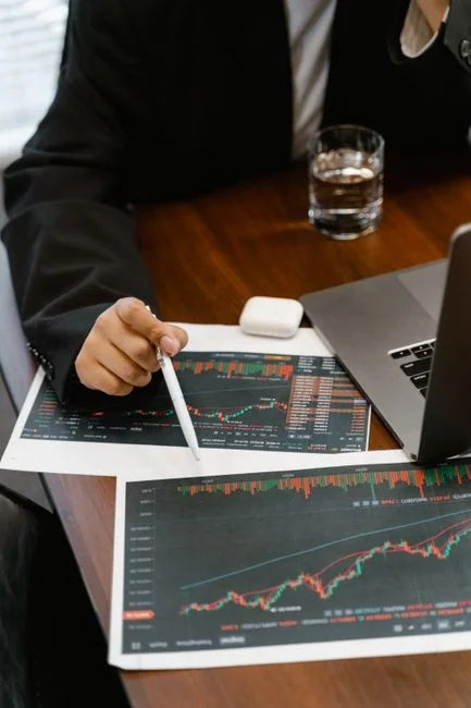 A modern workspace showing hands analyzing marketing data on a laptop and paper documents.