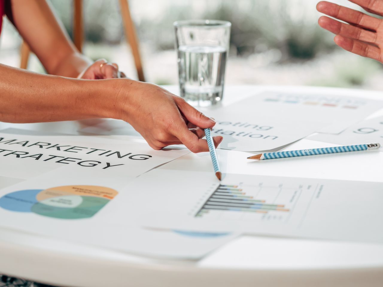 Hands reviewing marketing strategy with charts in an office environment.